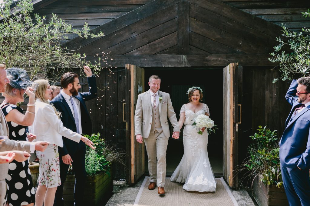 After their Hampton Manor wedding, a couple walk out of The Birches to confetti