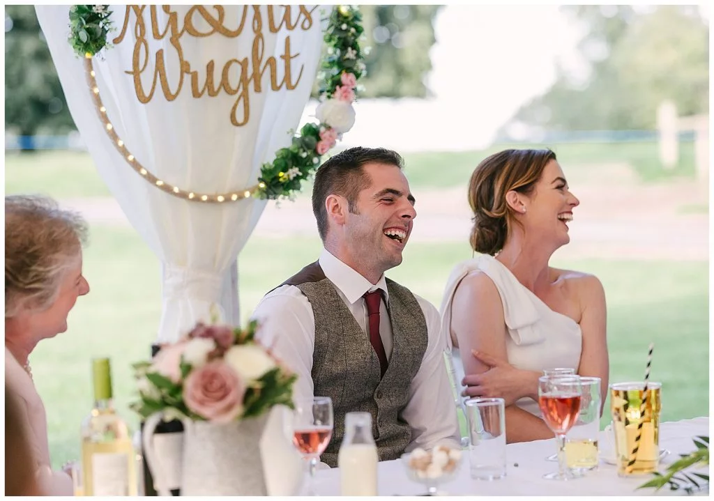 couple laughing during speeches on their wedding day