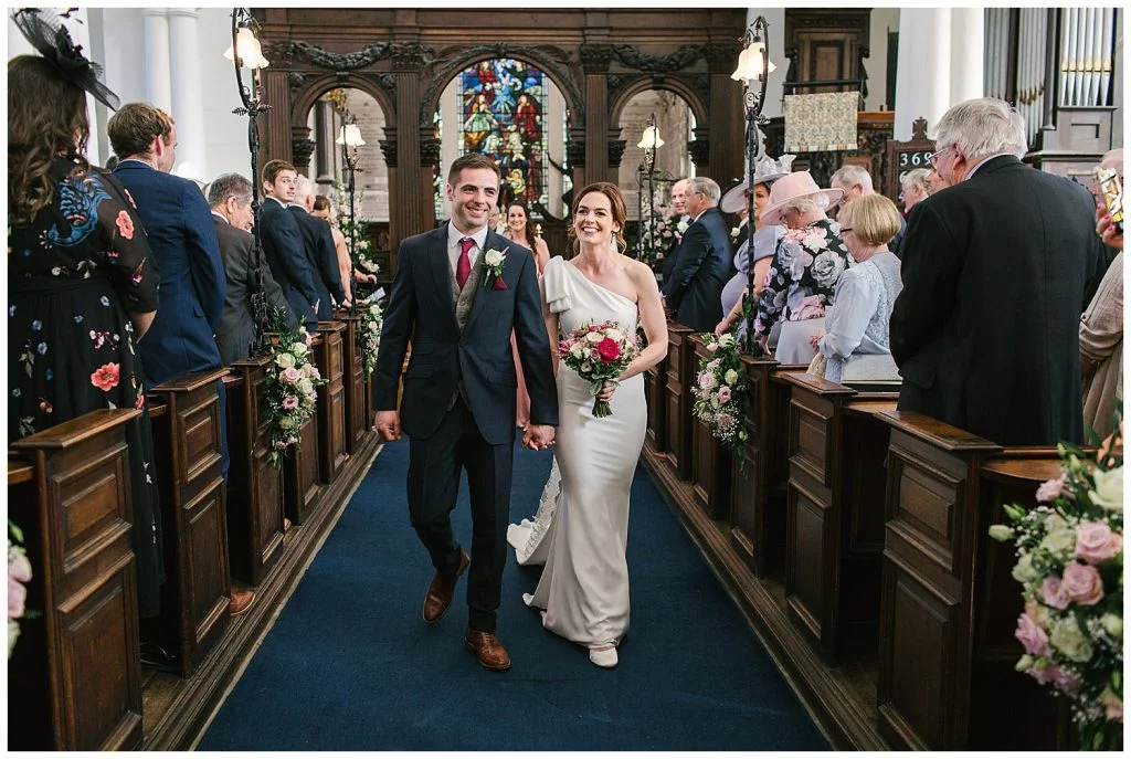 Smiling newlyweds walk down the aisle at Ingestre Church