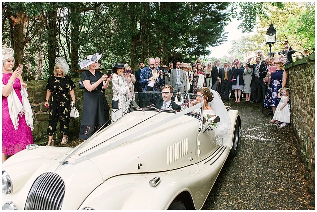 Bride and Groom Driving away from church in a vintage Morgan