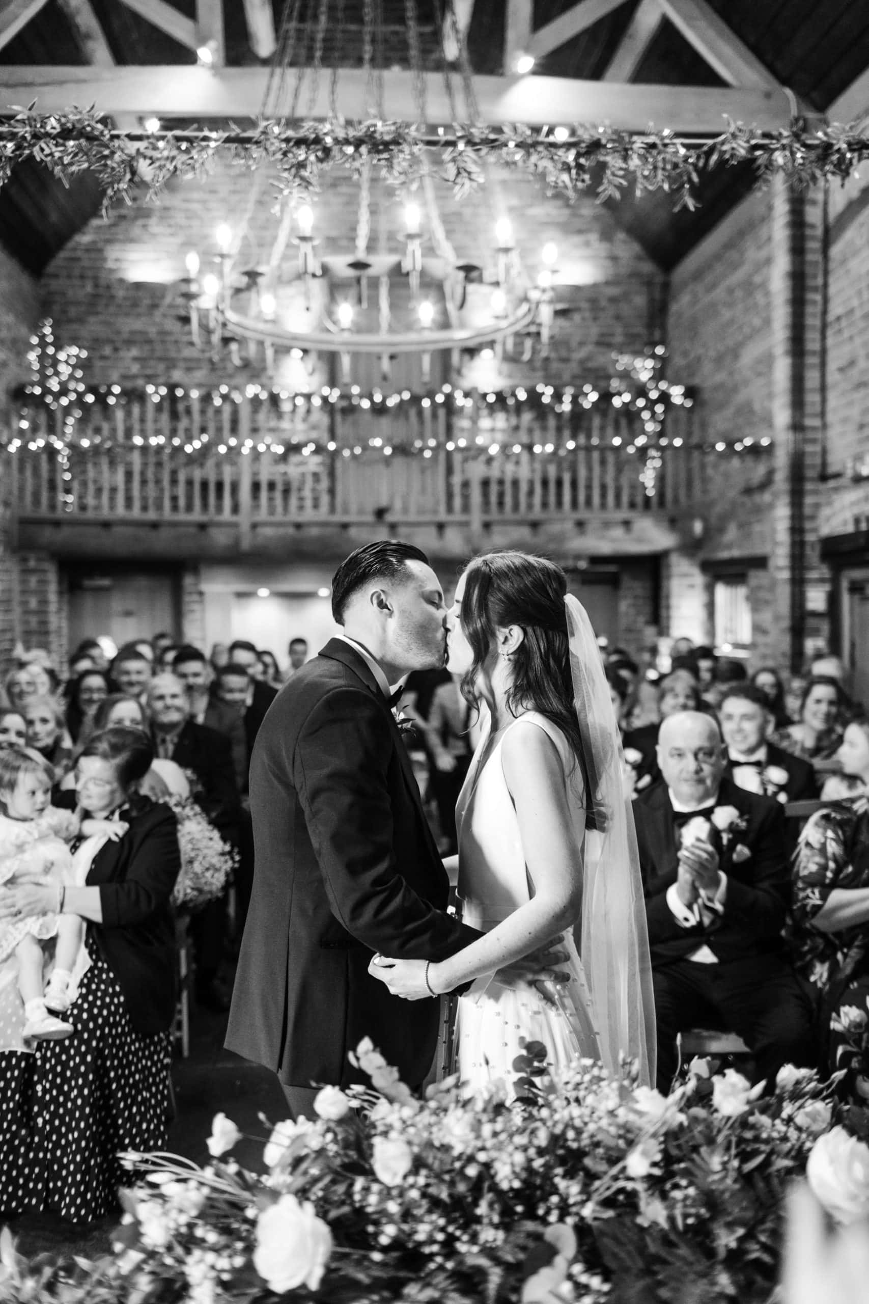 Couple kiss infant of their wedding guests in the Barley Barn