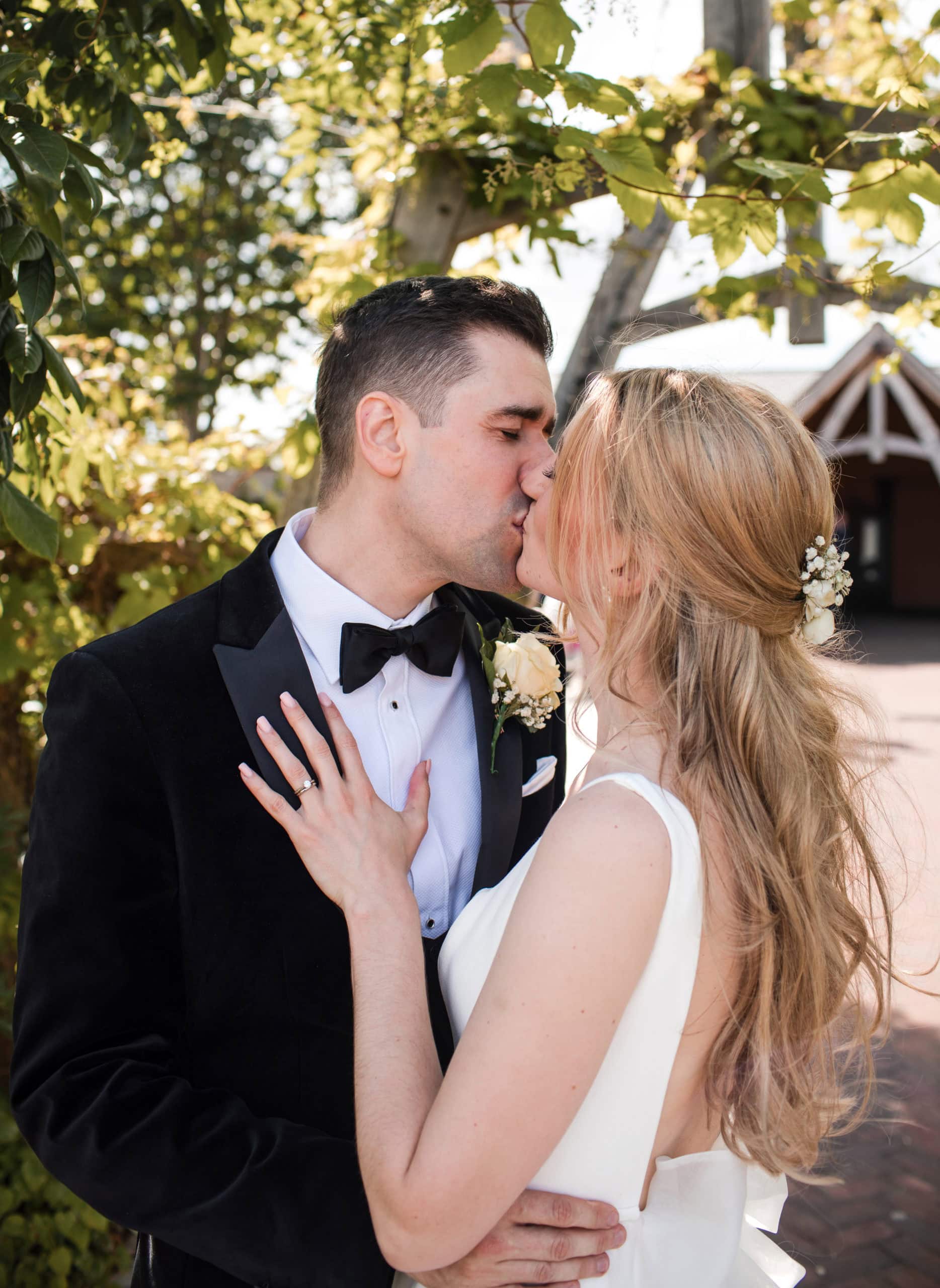 Bride & Groom share a kiss. Bride wears hair loose and Groom wears black tie