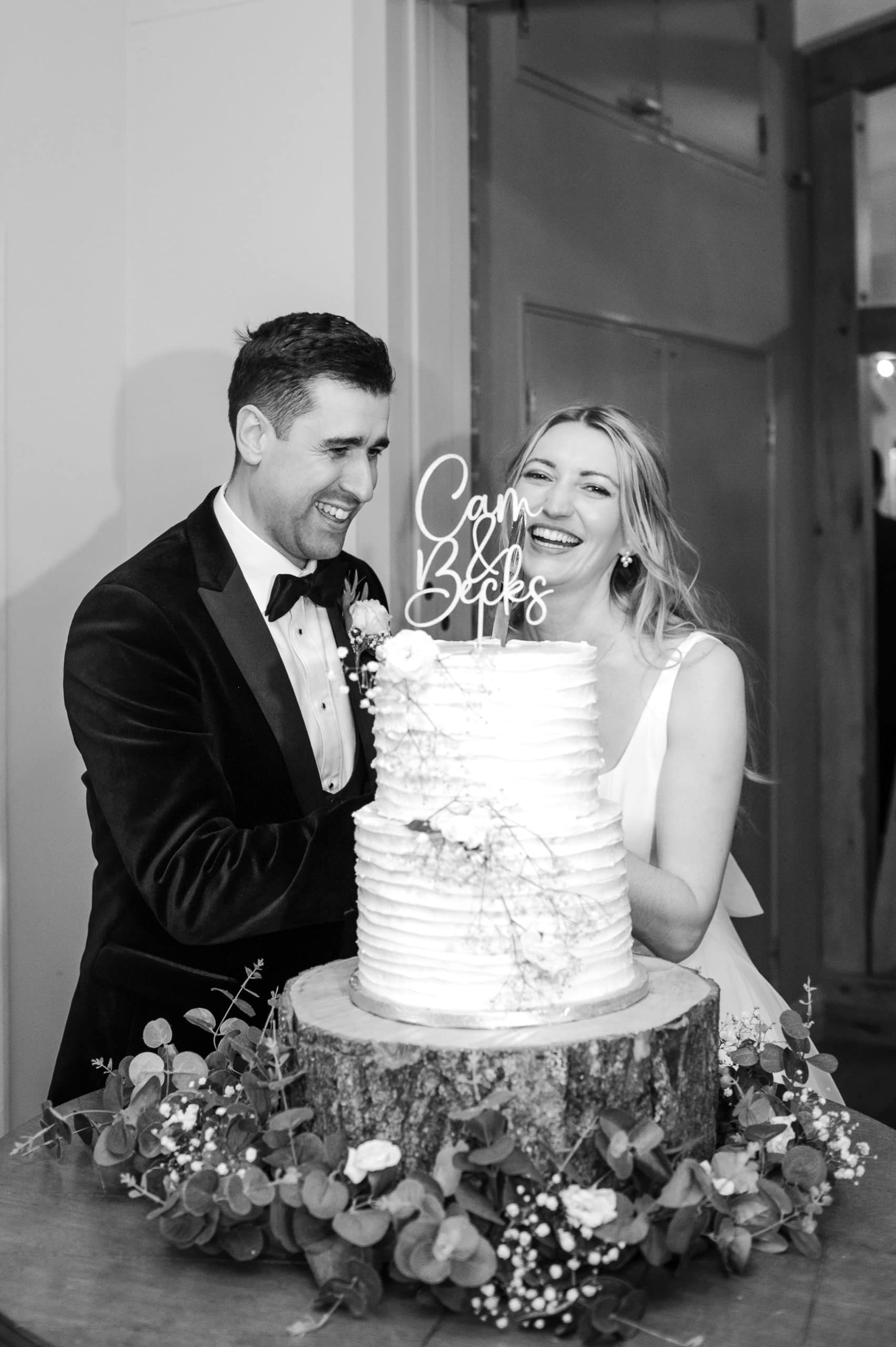 Happy laughing couple cut their wedding cake 