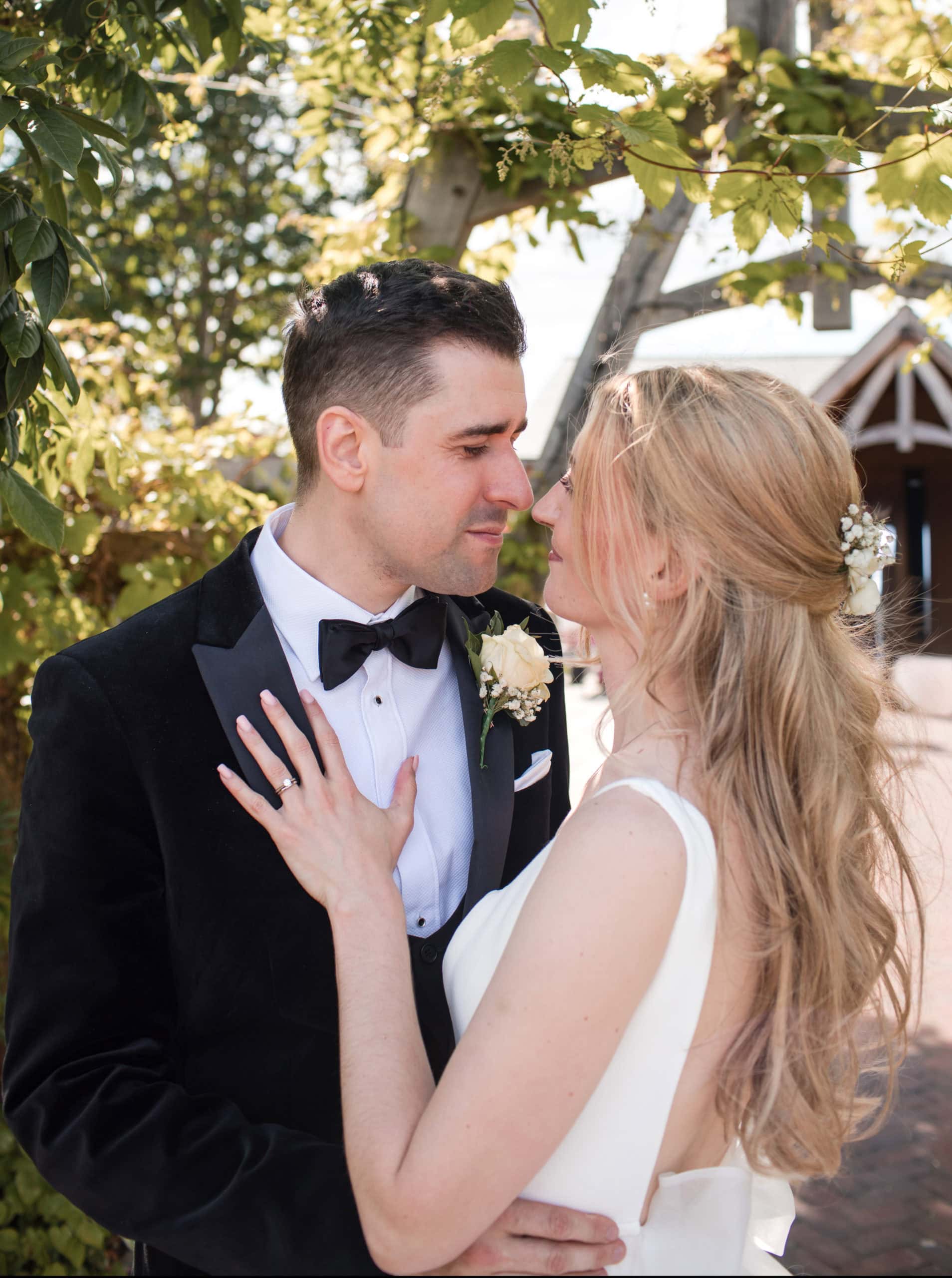 Couple stand under wooden arch and share a romantic moment at Cider Mill Barns