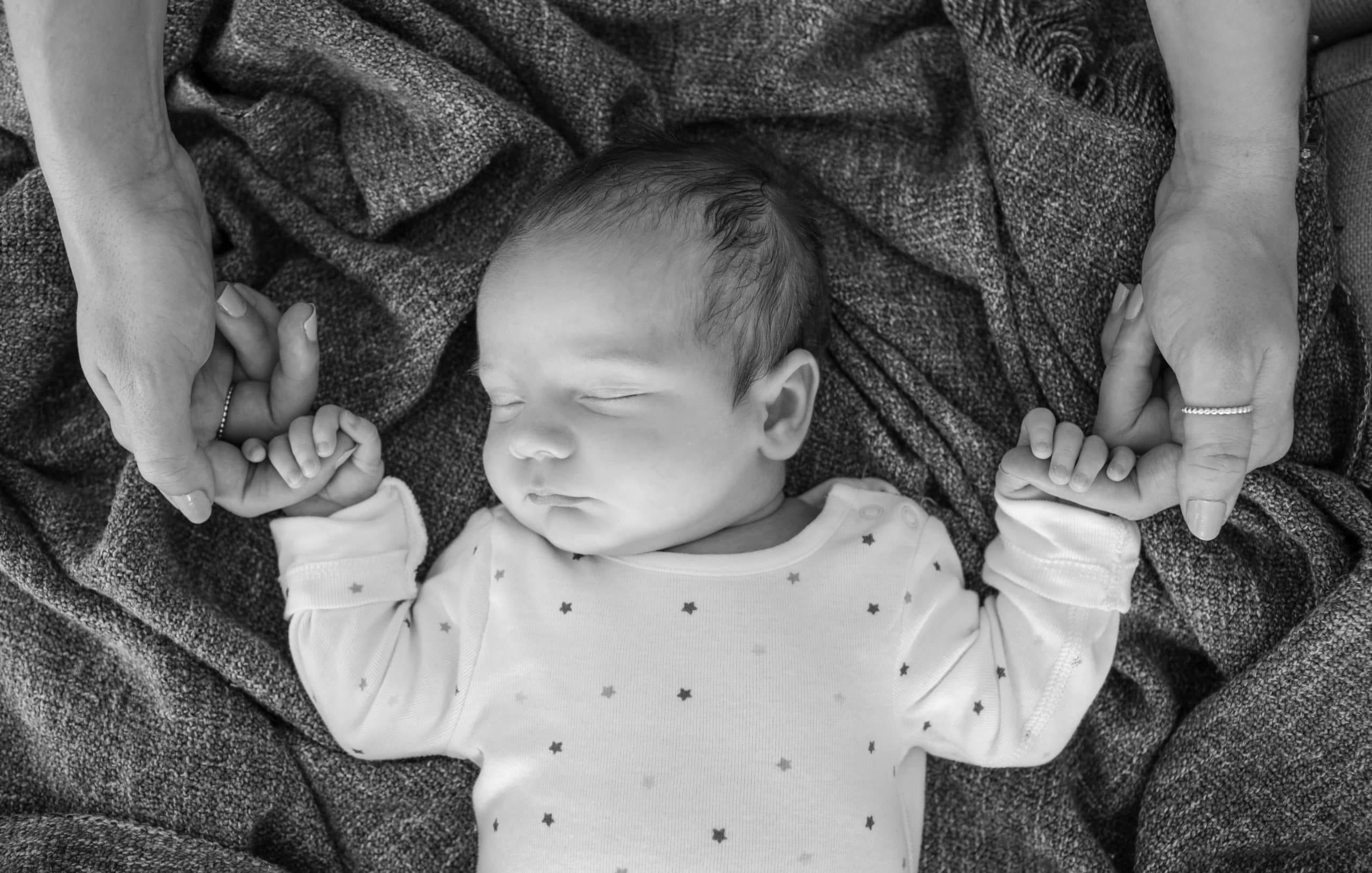 Newborn baby asleep wearing a white babygro